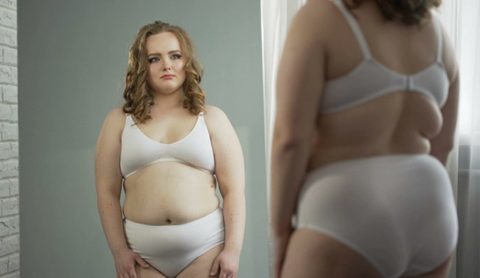 Girl in underwear in front of the mirror is fat