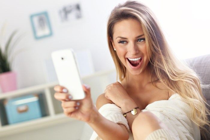The girl looks at the phone and smiles