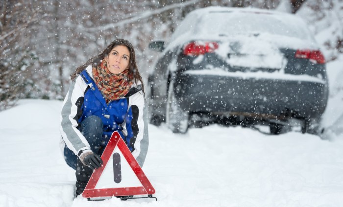 The girl pushes the car in winter