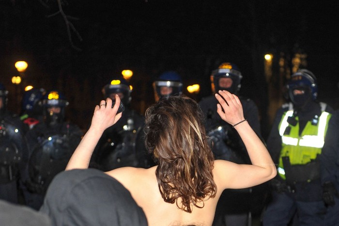 Women are police naked in skirts without a top put a criminal in a cage