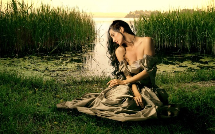 Girl in a dress sits on the grass