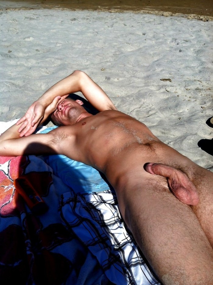 A naked guy lies on the beach