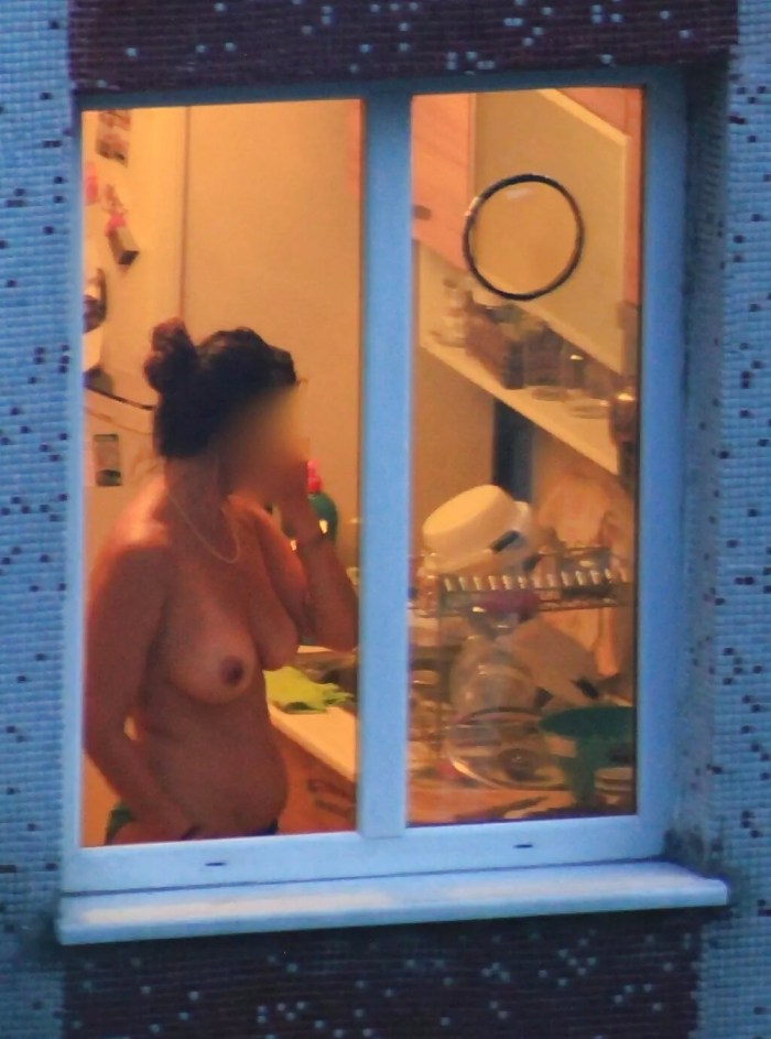 The girl undresses in the window