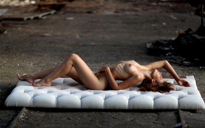 A naked woman lies on the couch
